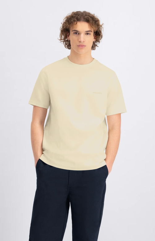 Man wearing a light-colored t-shirt and dark pants on a white background